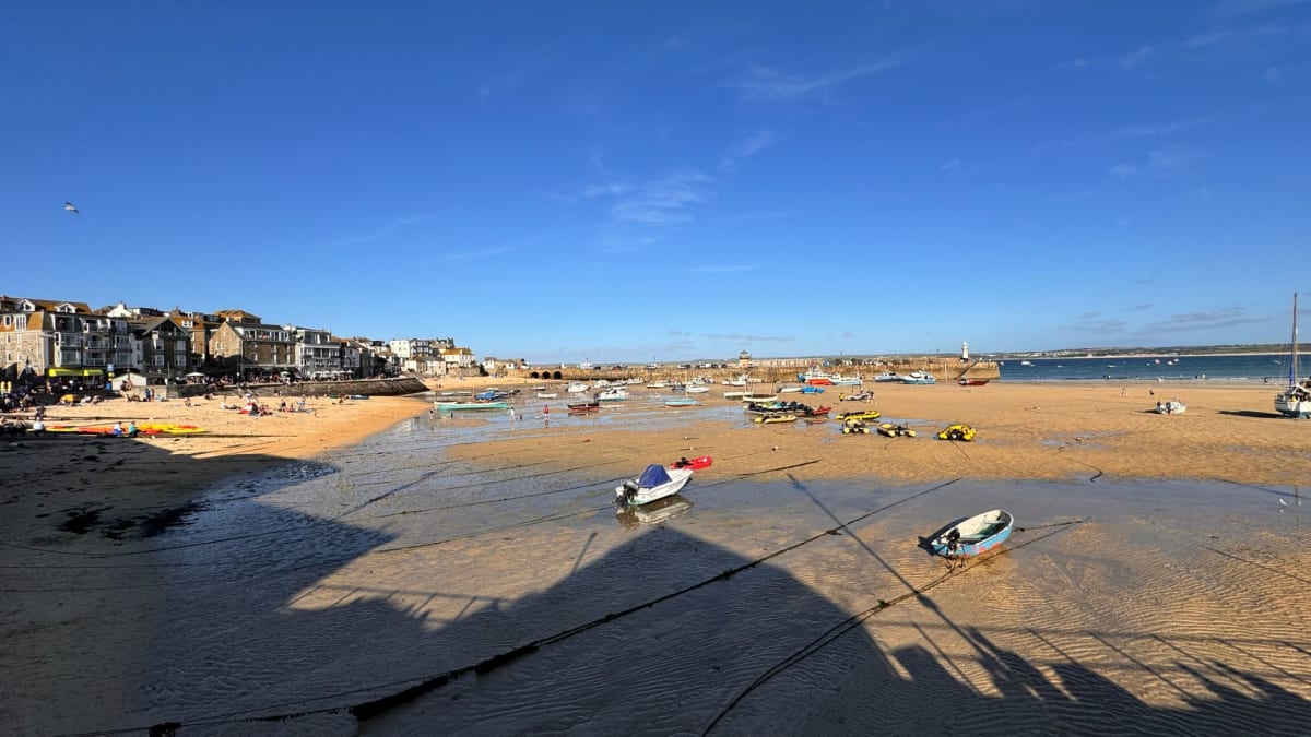 Playa de Porthmeor desde arriba, una larga franja de arena pálida con surfistas en el agua