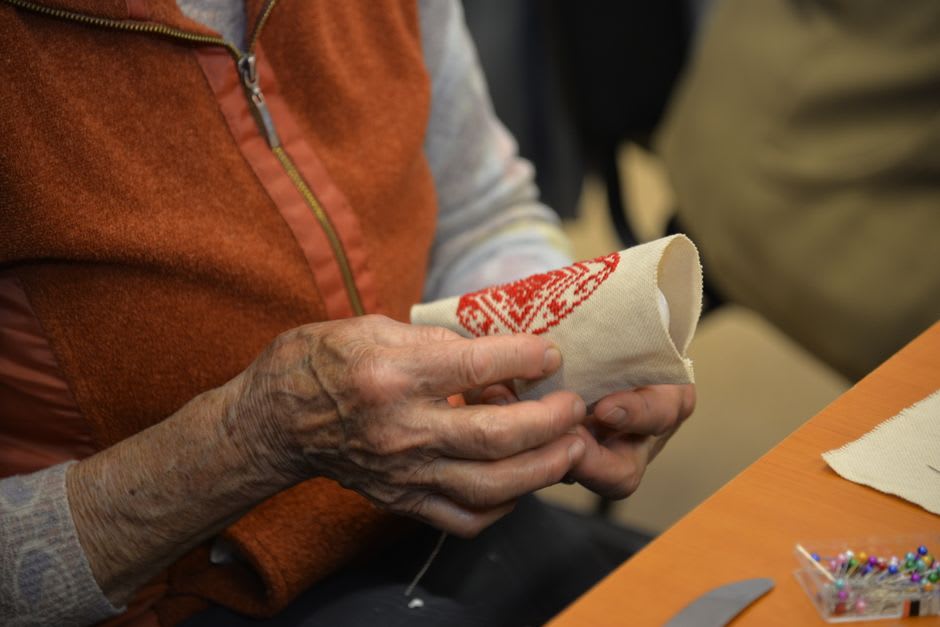 Elderly woman sitting in a doorway hand-stitching white lefkaritika lace