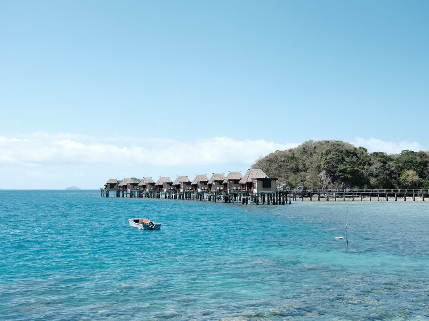 La diminuta South Sea Island bordeada de palmeras, vista desde el catamarán que se acerca, rodeada de agua turquesa somera