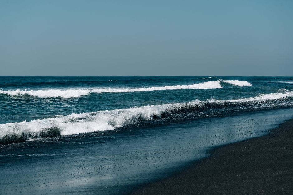 Des bateaux de pêche échoués sur le sable gris-doré de la plage de Wailoaloa, des pêcheurs triant la prise du matin