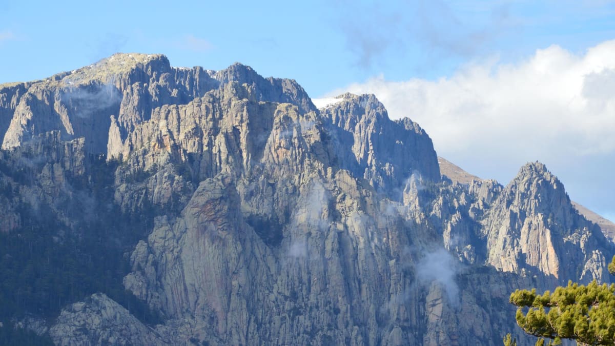 Les aiguilles de Bavella émergeant de la brume matinale, la forêt de pins laricio en contrebas et le ciel qui se dégage au-dessus d'elles