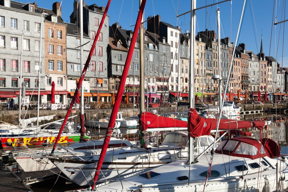 Sailboats moored in the Vieux Bassin harbour of Honfleur with narrow slate-fronted houses reflected in the water