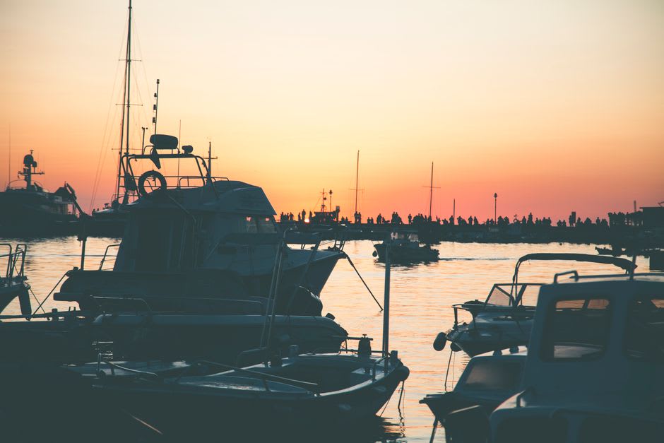 Des bateaux de pêche et des ferries de passagers amarrés côte à côte dans le port du Lavandou au lever du soleil