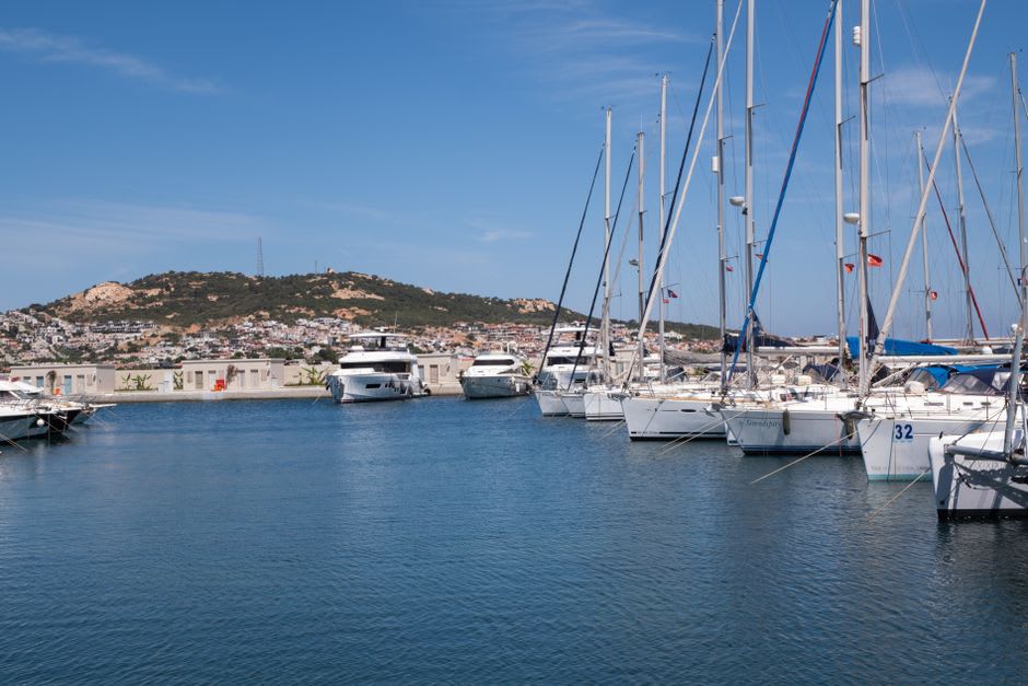 Voiliers et bateaux de pêche amarrés dans le port de la Napoule sous des collines couvertes de pins