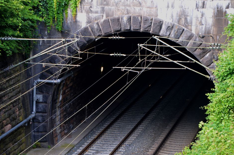 Des trains et des voies ferrées filant vers le sombre portail de pierre de l'entrée du tunnel du Fréjus près de Modane
