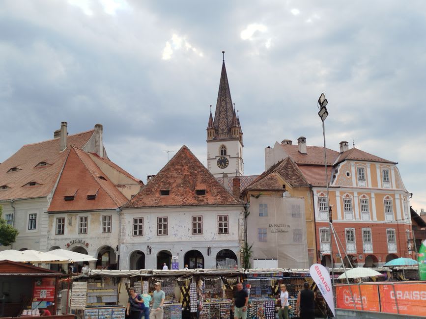 El pozo renacentista y los puestos de mercado en la plaza principal de Obernai con la torre medieval del campanario detrás