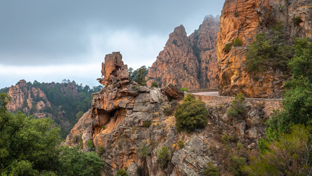 Les aiguilles de granit rouge des Calanques de Piana captant la lumière orange profonde de fin d'après-midi au-dessus de la mer