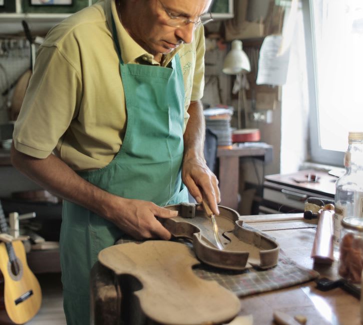 L'atelier d'un luthier à Pigna avec une cetera à moitié terminée et des outils de sculpture sur bois posés sur un établi près d'une porte ouverte