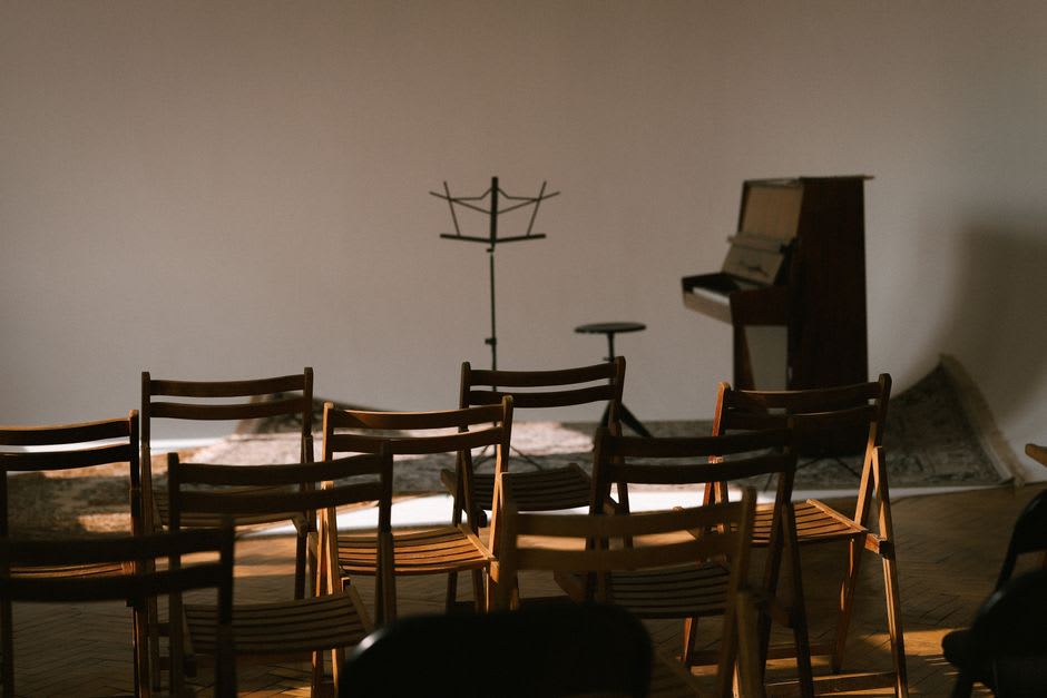 L'intérieur en pierre d'une chapelle de Pigna aménagée pour un concert de chant polyphonique en soirée, chaises disposées près d'une petite scène