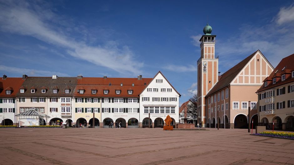 Les étals du marché dominical remplissant la place de Saint-Cyprien, avec les toits en gradins de la ville et le clocher de l'abbatiale se dressant derrière