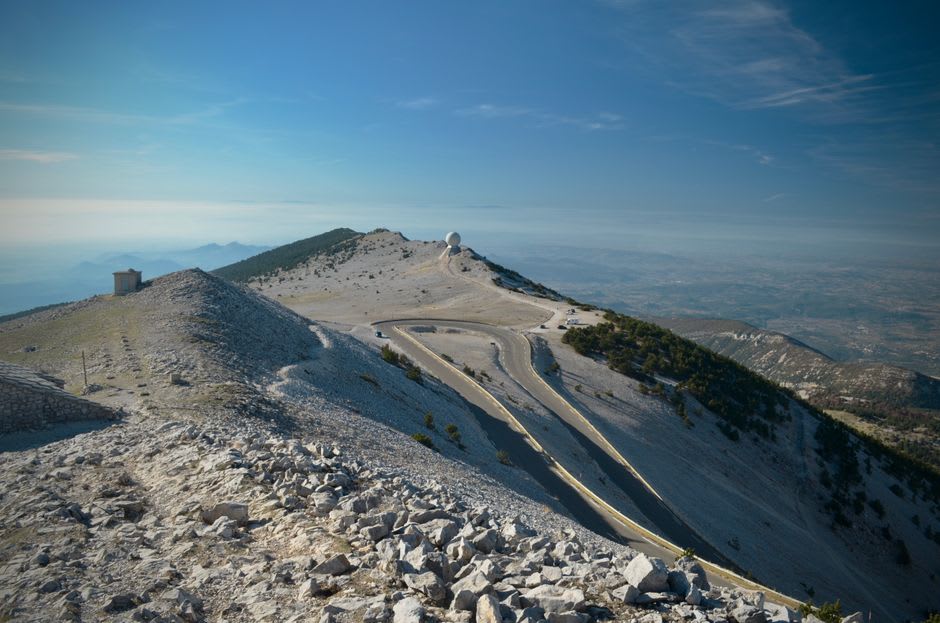 A dirt lane cutting between two lavender fields on the Sault plateau with Mont Ventoux's summit visible in the distance