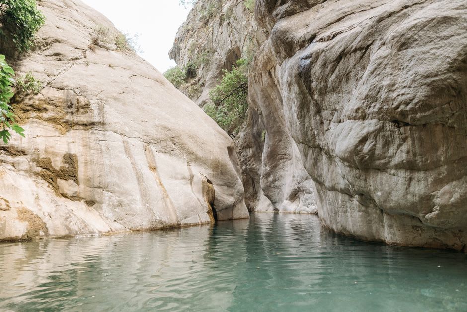 Une vasque naturelle en granite dans les gorges au-dessus de Solenzara remplie d'eau turquoise limpide, avec des rochers encadrant le lieu de baignade