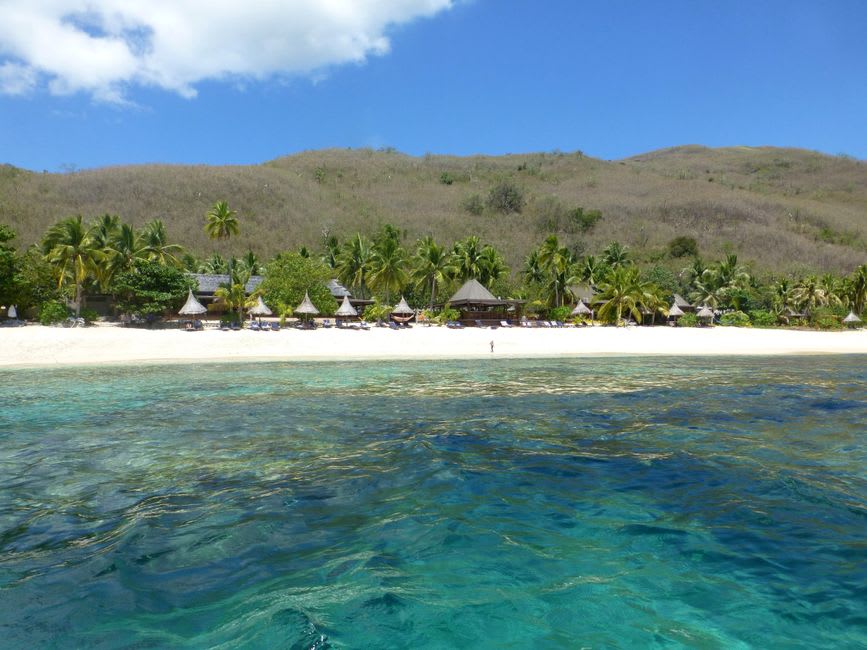 Hanamoenoa beach on Tahuata with unusually white sand, clear shallow water, and a boat anchored offshore