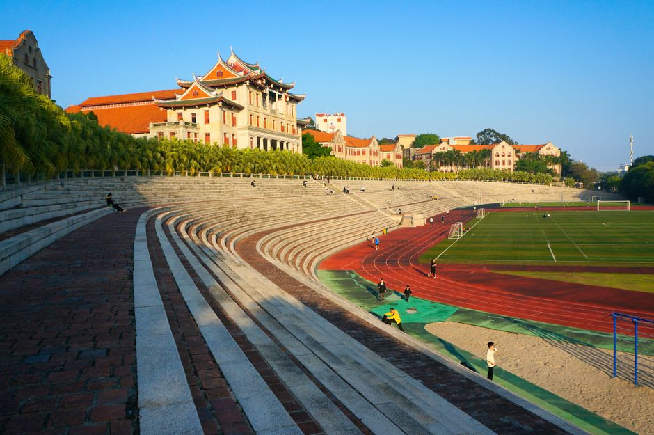 Students on the seawall rocks below Xiamen University's coastal campus buildings