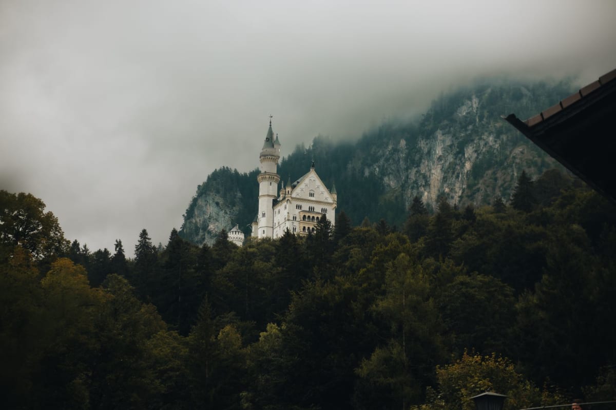 El castillo de Neuschwanstein emergiendo de la niebla sobre las estribaciones boscosas de Baviera