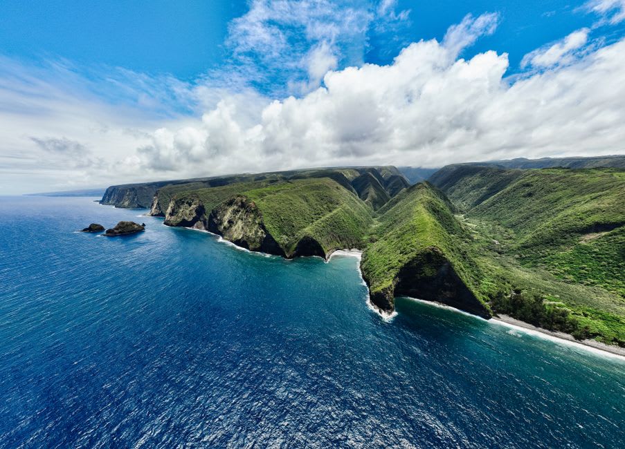 A waterfall cascading through dense jungle into a river pool along the Hamakua Coast