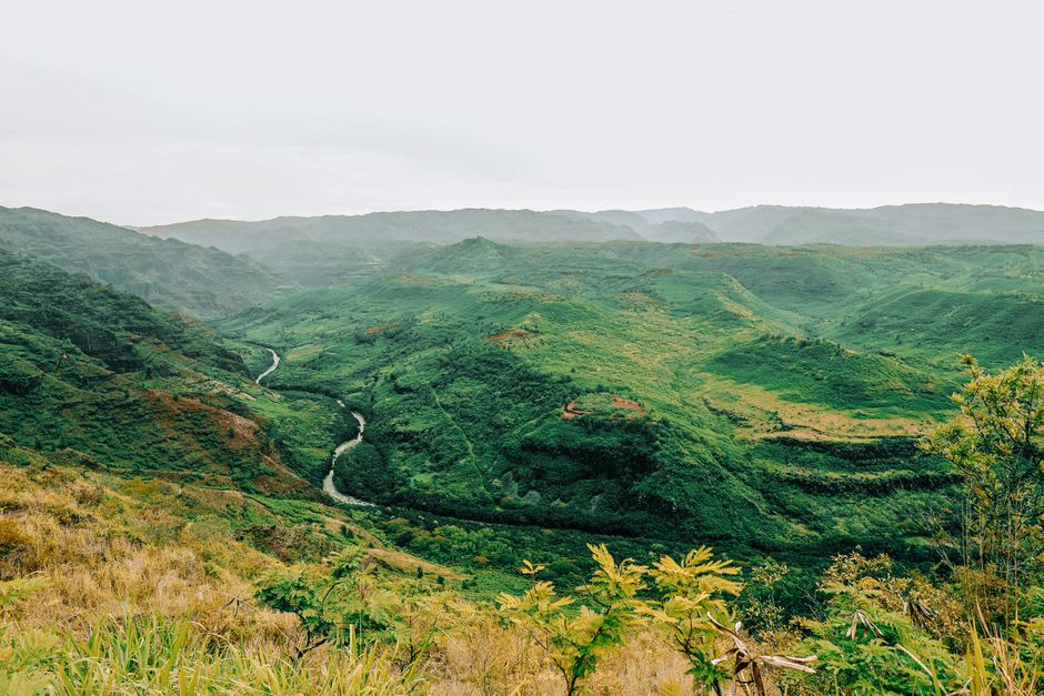 Black sand beach at Waipi'o Valley framed by steep green cliffs on both sides