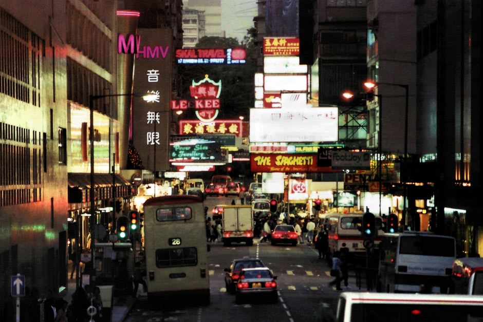 Nathan Road au niveau de la rue, avec une signalétique néon et des devantures se pressant des deux côtés d'un trottoir animé