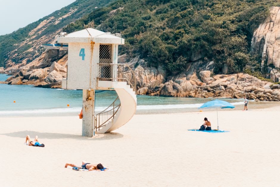 La playa principal de Shek O en una tarde entre semana, agua tranquila y un tramo de arena casi vacío
