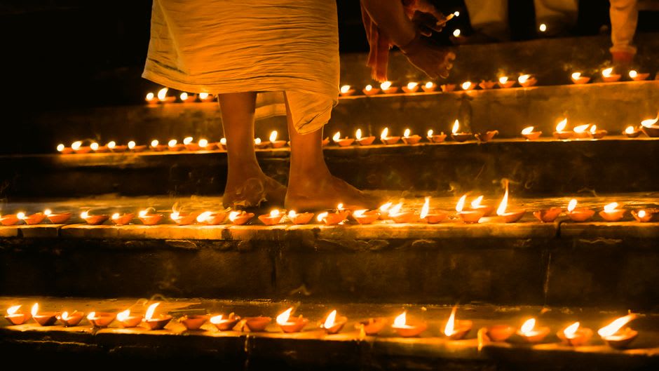 Oil lamps lit along the stone steps of Ramghat on the Mandakini River at dusk
