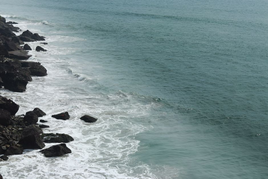 Backpacker cliff trail winding along red laterite rock above the Arabian Sea near Gokarna