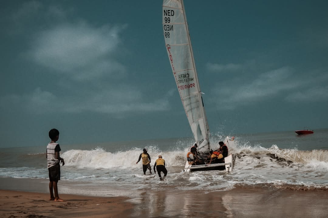 Fishermen pulling a wooden boat onto the sand at Kovalam's Lighthouse Beach at sunset