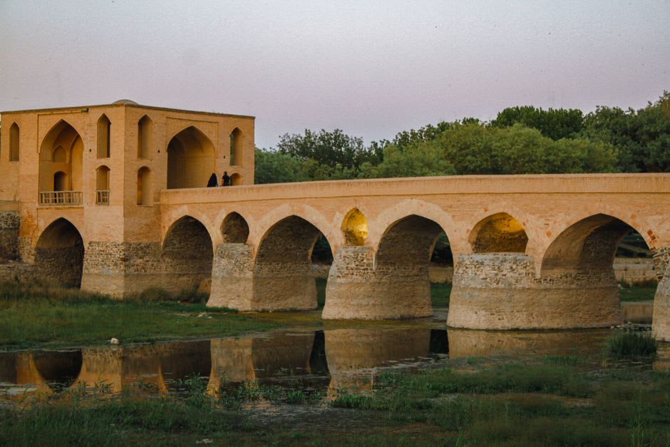 Los arcos de piedra de dos niveles del puente Khaju extendiéndose a través del río Zayandeh a la luz del día