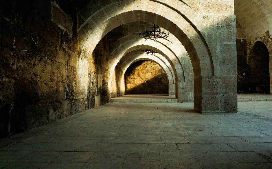 Vaulted stone corridor of the Crusader Knights' Halls beneath Akko's old city