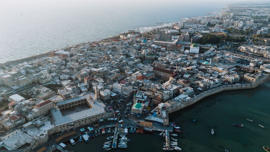 Fishing boats moored in Akko's old harbor beneath stone Ottoman fortifications