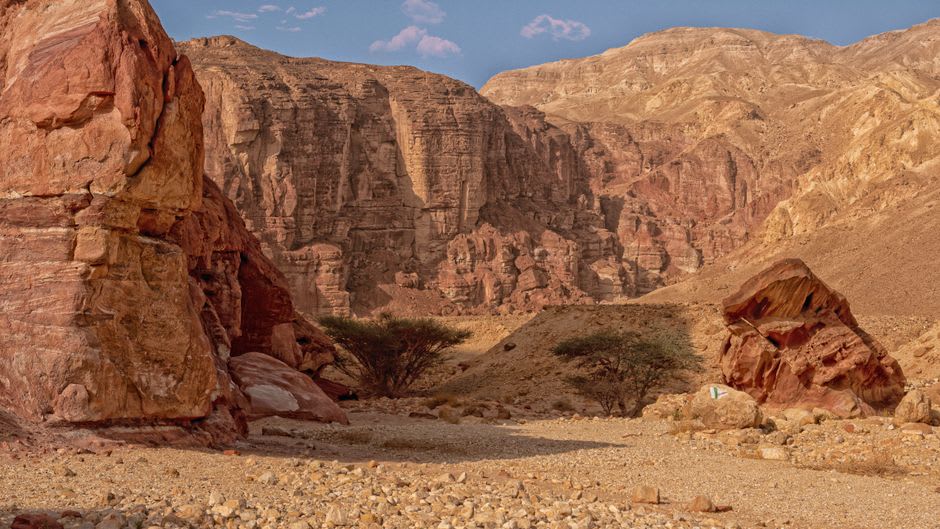 Striped, colorful rock formations along a hiking trail descending into Ramon Crater