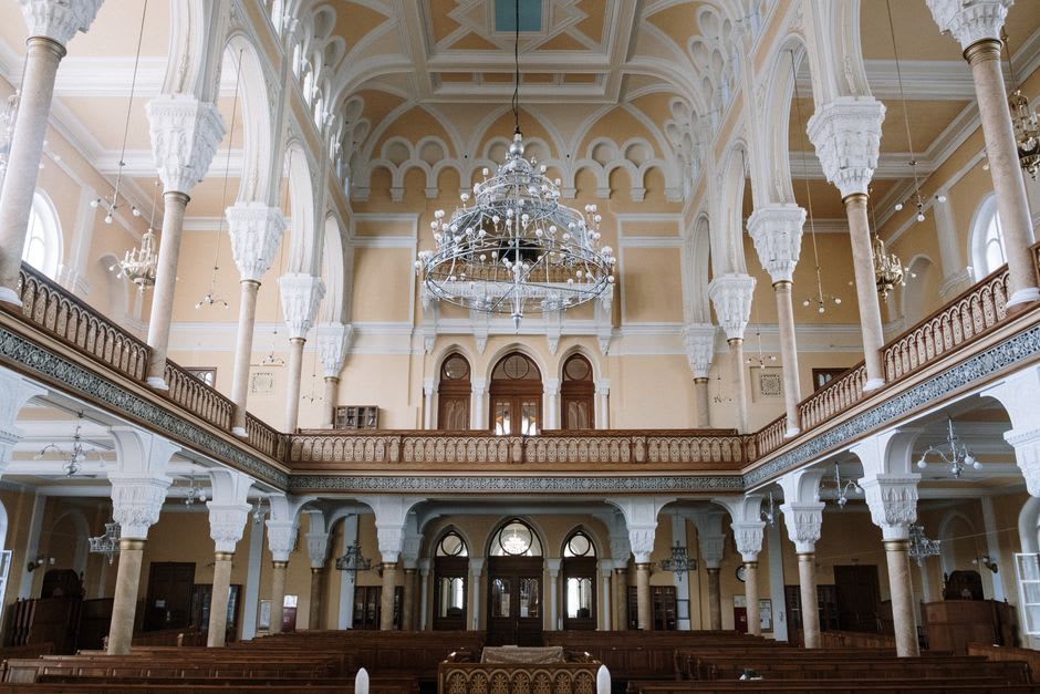 Interior of a centuries-old synagogue in Tzfat with worn stone arches and soft light