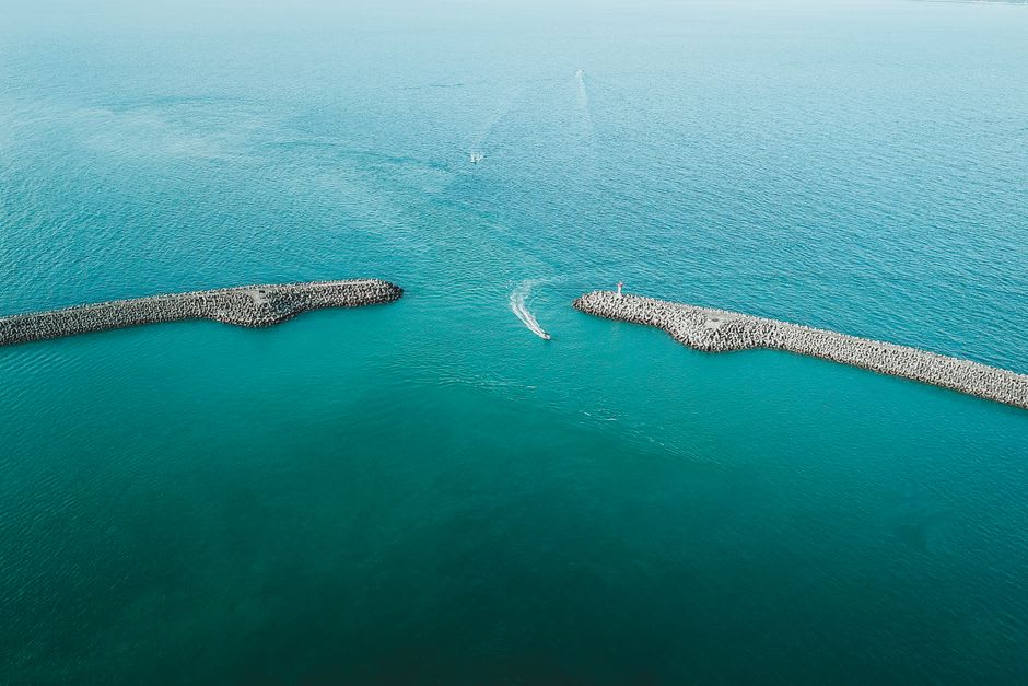 La digue paisible du port d'Aoshima avec de petits bateaux de pêche et l'étendue ouverte de la mer d'Uwa