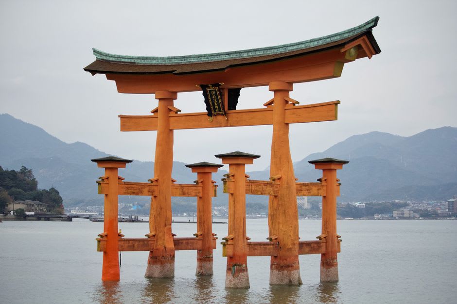 Discos de arcilla de la fortuna suspendidos en el aire sobre el agua hacia un pequeño torii bajo el santuario de Chikubushima