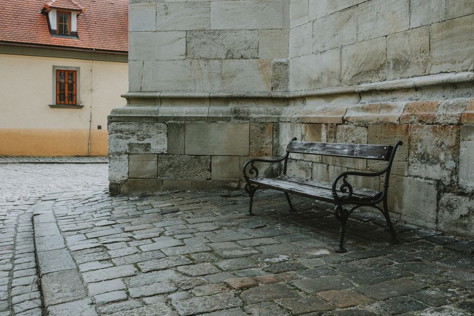 Un banco de piedra tranquilo a lo largo de la calle samurái de Chiran, tazas de té dispuestas junto a un muro bajo de jardín en la luz de la tarde