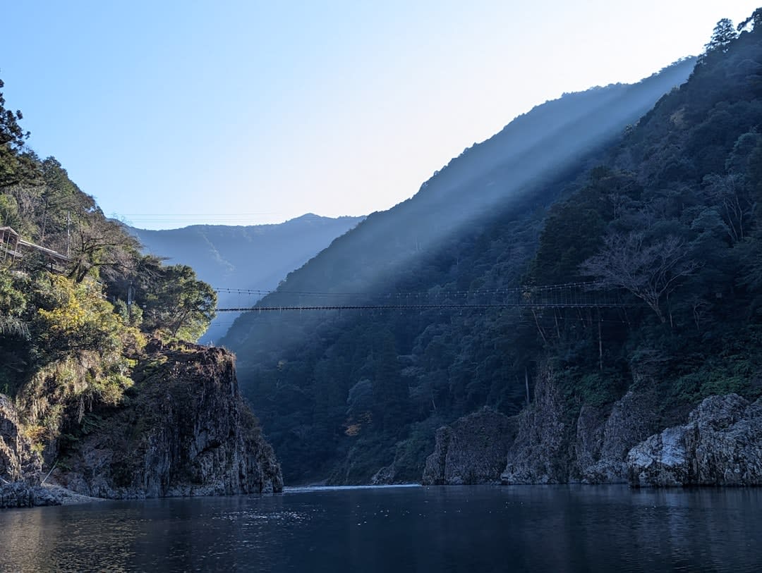 Un bateau touristique glissant à travers les gorges d'Enakyō près d'Ena, hautes falaises de granit érodé s'élevant à pic depuis l'eau verte et immobile