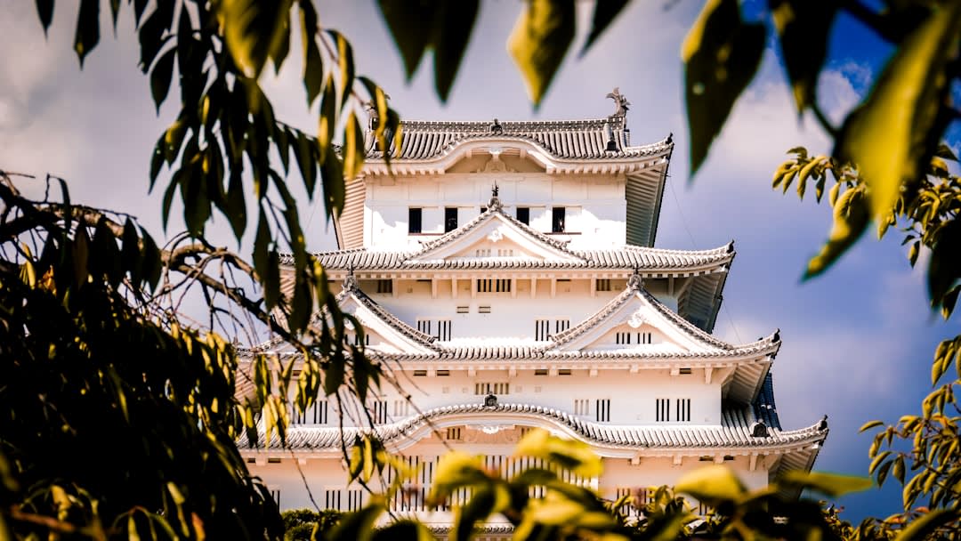 La torre blanca de varios niveles del castillo de Himeji vista a través de sus murallas de piedra y patios