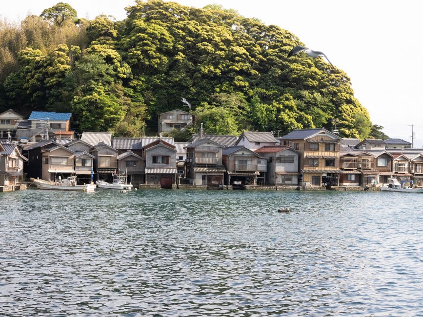 Open ground-floor boat garage of a funaya with a fishing vessel and nets at the waterline in Ine