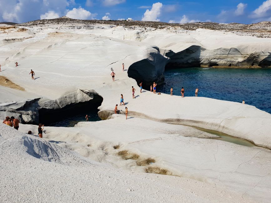 Des baigneurs dans l'eau claire de la plage de Jodogahama sous de hautes pointes de roche blanche