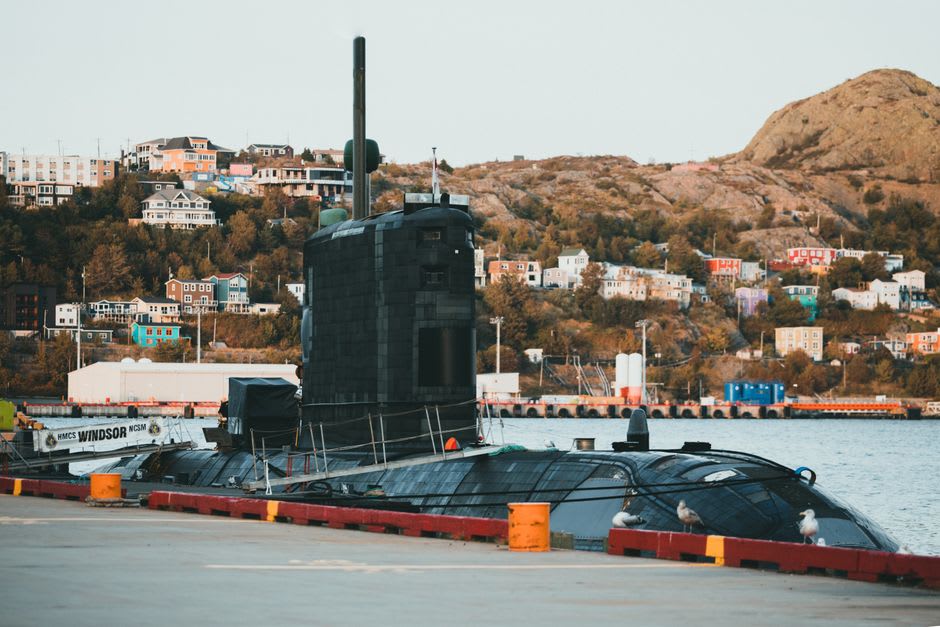 Un buque naval gris y un submarino amarrados en el puerto activo de Kure, vistos desde un barco turístico en un día nublado