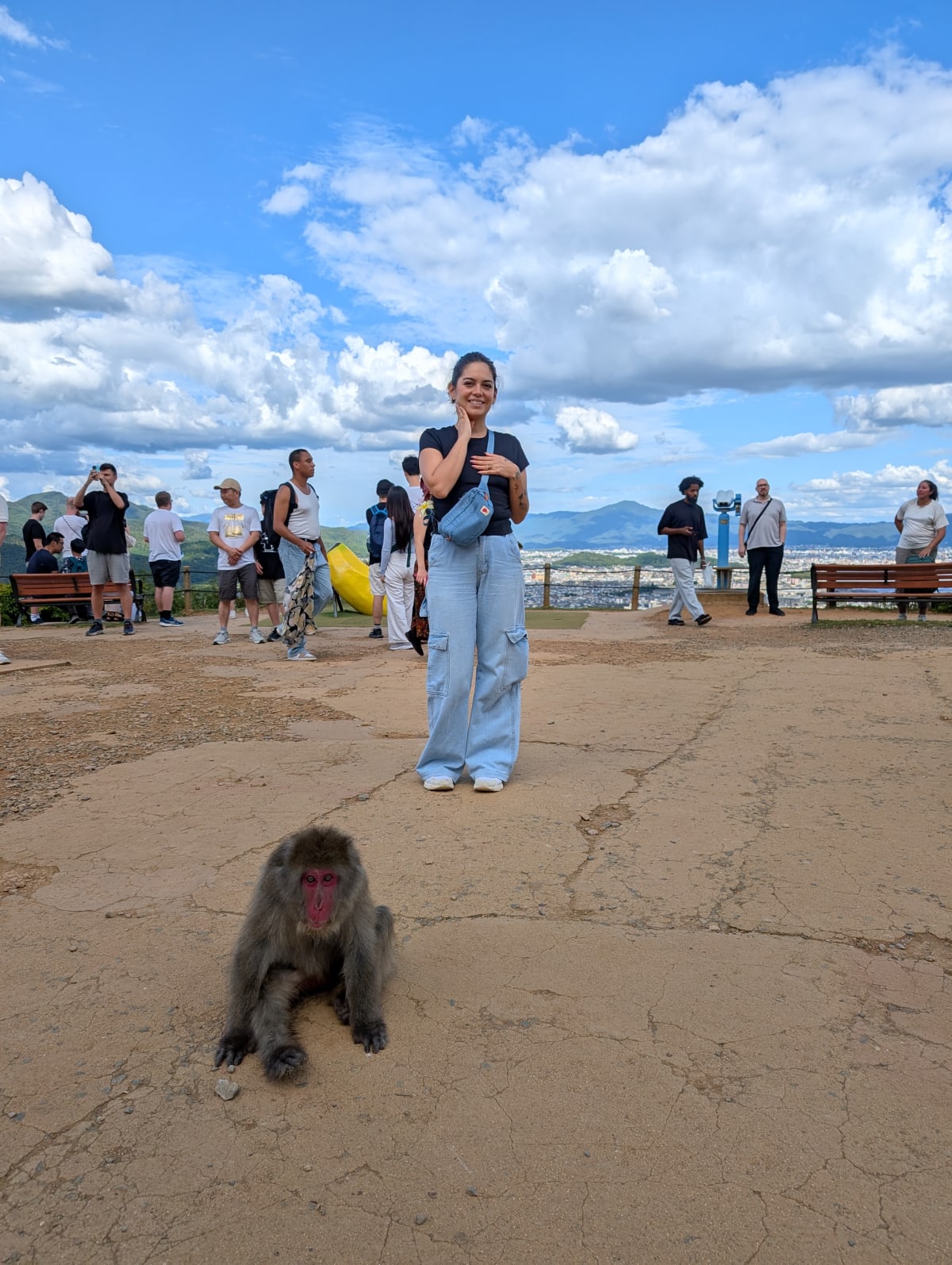 Lia at the summit of the Iwatayama Monkey Park — laughing, a macaque sitting at her feet, all of Kyoto and the mountains stretching behind them