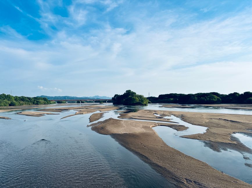 Le banc de sable menant à Mitsukejima exposé à marée basse, des visiteurs traversant le sable compact vers l'îlot rocheux couronné de pins