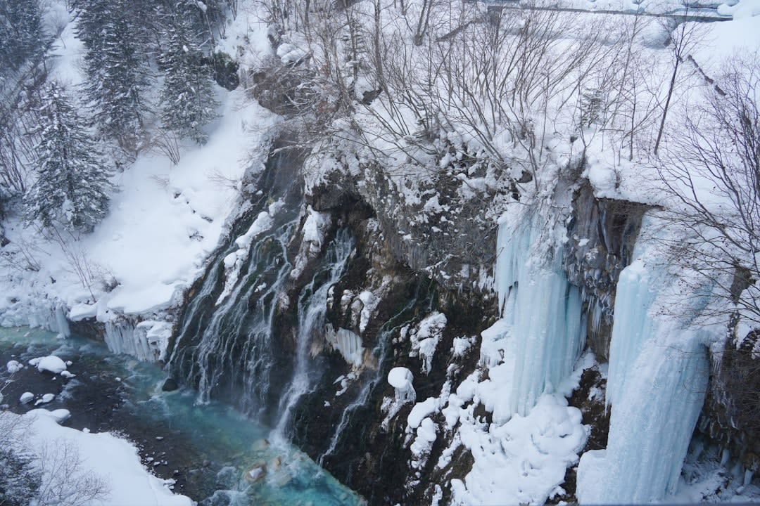 Des passerelles serpentant à travers la roche volcanique rouge et grise fumante du cratère de Jigokudani à Noboribetsu, fumerolles de soufre sous un soleil bas