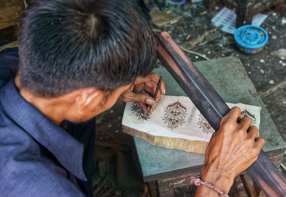 Un artesano tallando intrincados patrones en una piedra de tinta de pizarra oscura en un taller reconstruido de Ogatsu