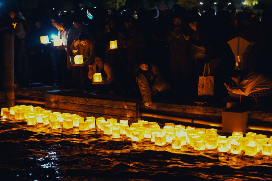 Des lanternes flottantes kiriko illuminées portées dans l'eau peu profonde pendant une procession de festival près de Suzu