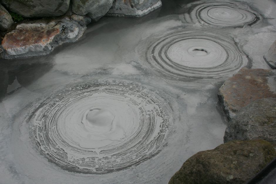 Personas tendidas y envueltas en esteras de paja sobre roca volcánica caliente en la zona de ganban-yoku de Tamagawa Onsen