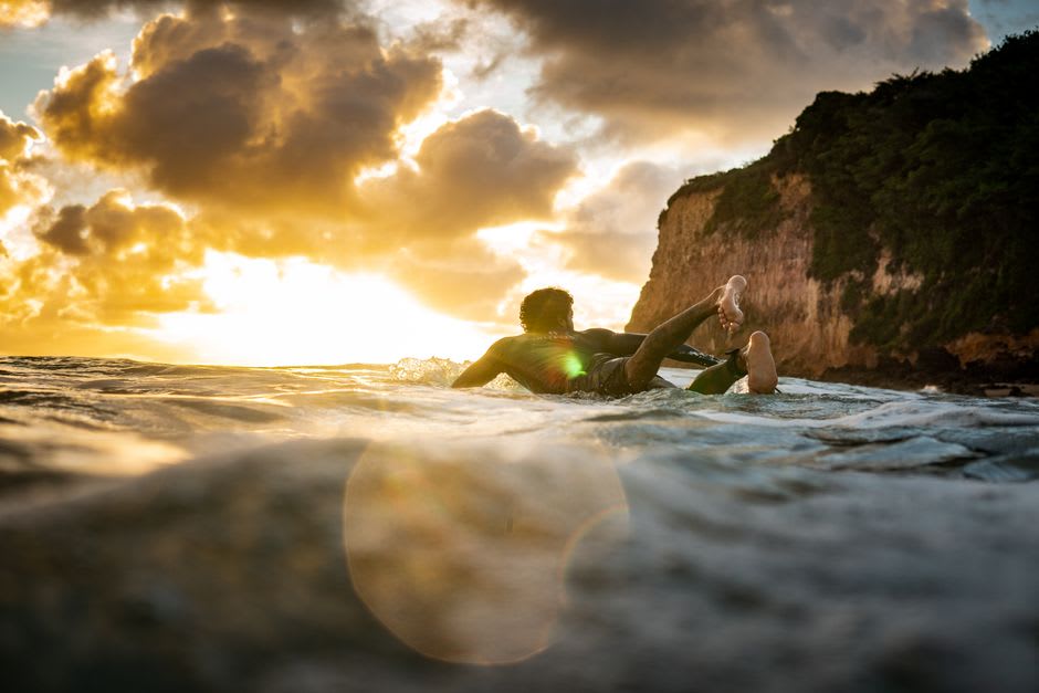 Lia remando hacia el mar en una playa amplia de arena en Tanegashima durante la hora dorada