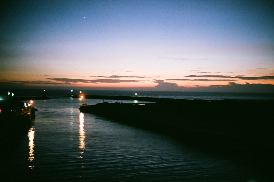 La baie de Nanao au coucher du soleil vue depuis le front de mer de Wakura Onsen, lumière rose sur une eau calme là où les sources chaudes sous-marines remontent
