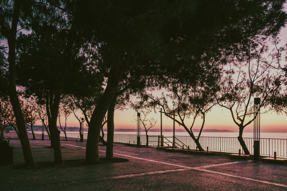 La promenade du front de mer de Wakura Onsen au crépuscule, les lumières des ryokan se reflétant dans la baie de Nanao alors que les bateaux de pêche rentrent