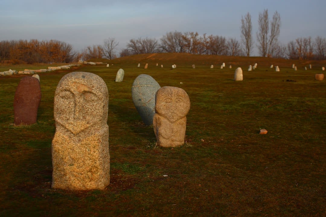 Hileras de balbales de piedra tallada de pie en la hierba cerca de la Torre Burana