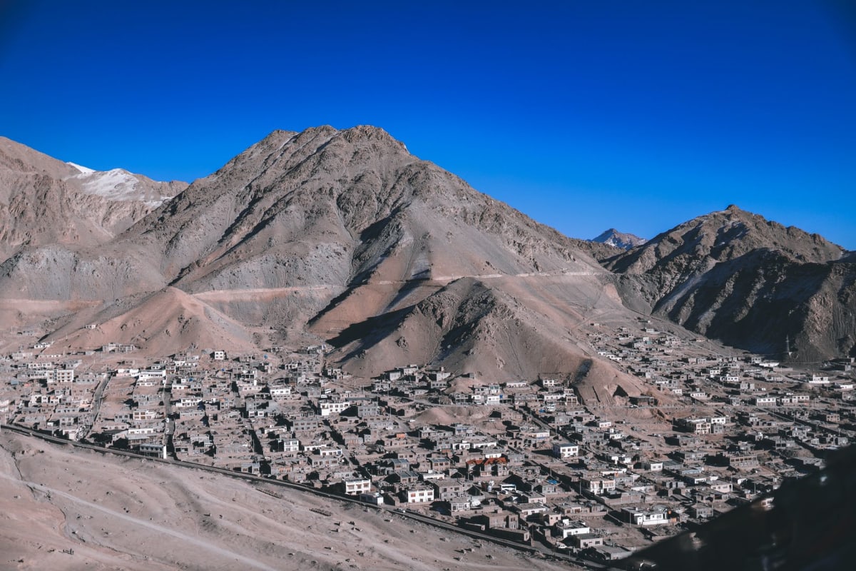 Leh Palace terrace at dusk, the Indus Valley spread below, distant peaks catching the last pink light